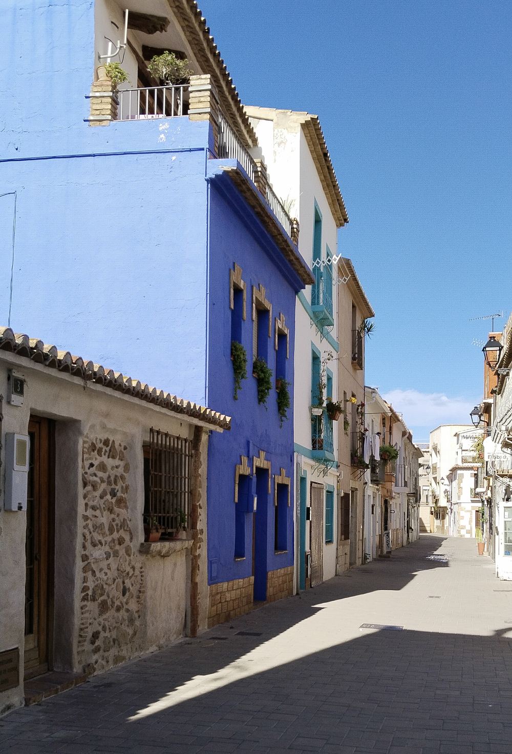 Calle del barrio de Baix la Mar, en Dénia, con fachadas de colores y ventanas